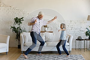 Happy active grandpa and cheerful grandkid dancing to music