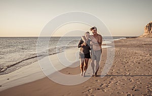 Happy active and healthy mature couple walking on the beach enjoying outdoors lifestyle