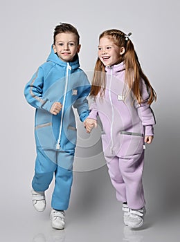 Happy active kids boy and girl in modern blue and pink jumpsuits play and walk together, having fun