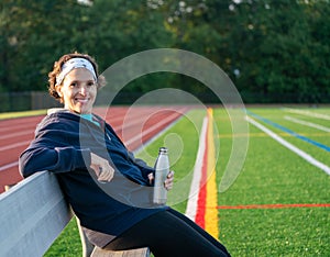 Happy Active middle age woman sitting by a track