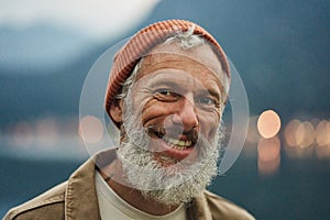 Happy active older man traveler standing in nature park. Close up portrait