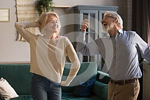 Happy active retired elder couple dancing together in living room