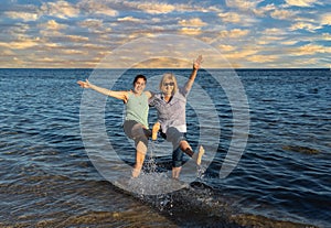 Happy active senior and adult daughter having fun together in summer beach on sunny day