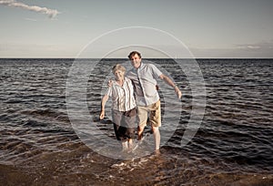 Happy active senior couple having fun together bay the sea in summer beach on sunny day