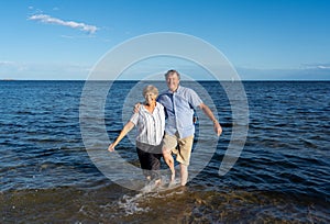 Happy active senior couple having fun together bay the sea in summer beach on sunny day