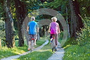 Happy and active senior couple riding bicycles outdoors in the park