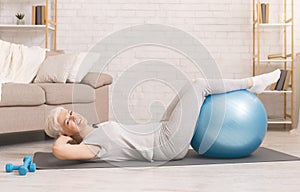 Happy active senior woman doing exercises with fitness ball