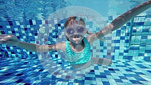 Happy active underwater child swimming in pool at the day time.