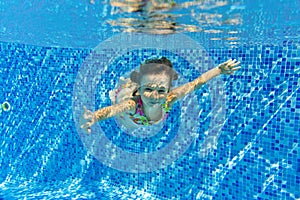 Happy active underwater child swims and dives in pool