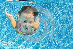 Happy active underwater child swims and dives in pool