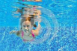 Happy active underwater child swims and dives in pool