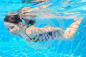 Happy active underwater child swims in pool