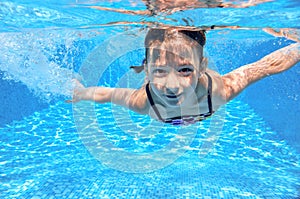 Happy active underwater child swims in pool