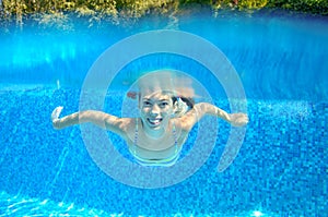 Happy active underwater child swims in pool