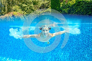 Happy active underwater child swims in pool