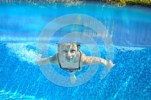 Happy active underwater child swims in pool