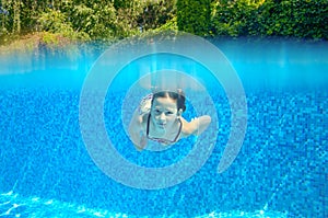 Happy active underwater child swims in pool