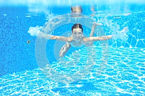 Happy active underwater child swims in pool, beautiful healthy girl swimming