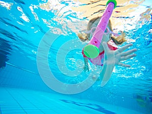 Happy active underwater child swims in pool, beautiful healthy girl swimming and having fun on family summer vacation, kids sport