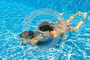 Happy active underwater children swim in pool