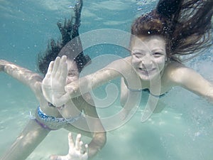 Happy active underwater girls swimming in sea and having fun on family summer vacation