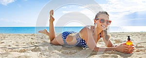 Happy active woman in beachwear on beach with sun screen laying