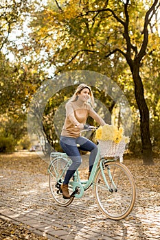 Happy active woman riding bicycle in autumn park