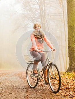 Happy active woman riding bike in autumn park.