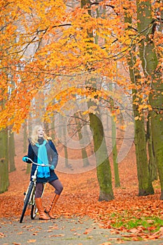 Happy active woman riding bike in autumn park.