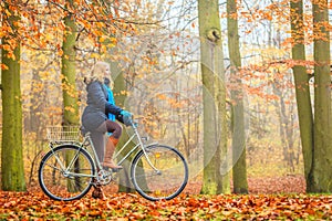 Happy active woman riding bike in autumn park.