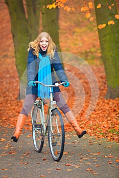 Happy active woman riding bike in autumn park.