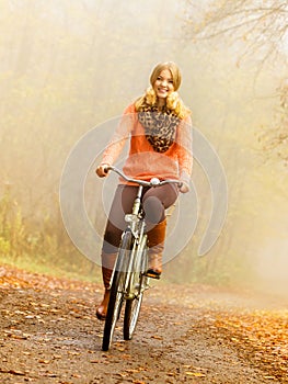 Happy active woman riding bike in autumn park.