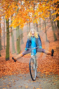 Happy active woman riding bike in autumn park.