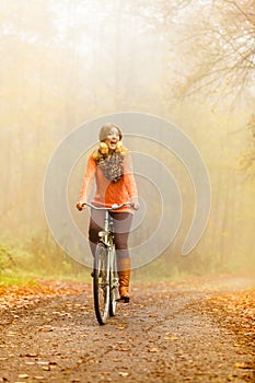 Happy active woman riding bike in autumn park.