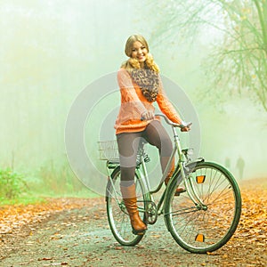 Happy active woman riding bike in autumn park.