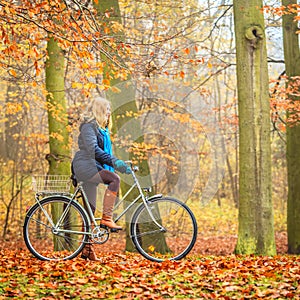 Happy active woman riding bike in autumn park.