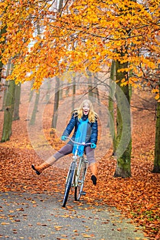 Happy active woman riding bike in autumn park.