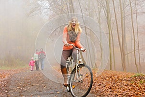 Happy active woman riding bike in autumn park.