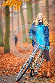 Happy active woman riding bike in autumn park.