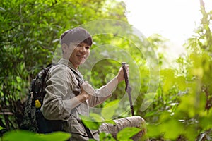 A happy and active young Asian male hiker with a backpack hiking in the forest alone