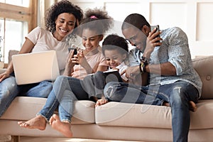 Happy addicted to gadgets black family using different devices.