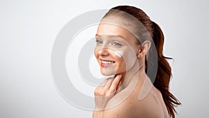 Happy Adolescent Girl Posing With Heart-Shaped Moisturizer On Face, Studio