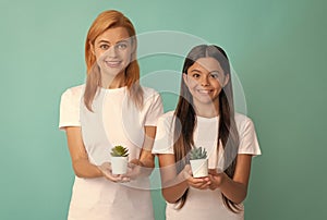 Happy adoptive family of adopted daughter child and woman mother smile holding houseplants, adoption