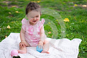 happy and adorable 7 or 8 months old baby girl playing with ball toy cheerful sitting on towel lying on grass city park in