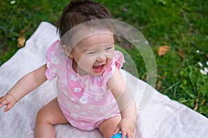 happy and adorable 7 or 8 months old baby girl playing with ball toy cheerful sitting on towel lying on grass city park in