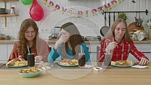 Happy adorable adolescent female friends having meal at birthday party