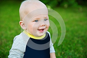 Happy adorable baby boy sitting on the grass