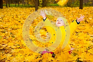 Happy adorable child girl with leaves in autumn park. Fall.The concept of childhood