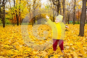 Happy adorable child girl with leaves in autumn park. Fall.The concept of childhood