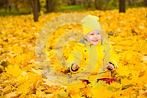 Happy adorable child girl with leaves in autumn park. Fall.The concept of childhood
